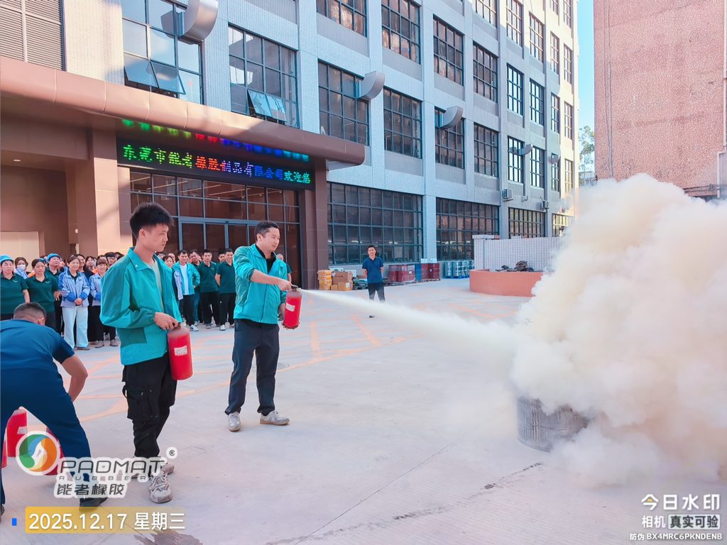 Employees practicing fire extinguisher operation during factory fire safety training and on-site fire drill.