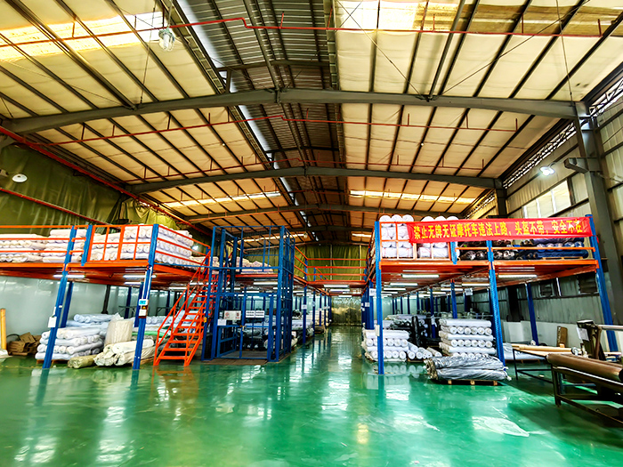 Spacious warehouse with mezzanine racks for mouse pad raw material storage.